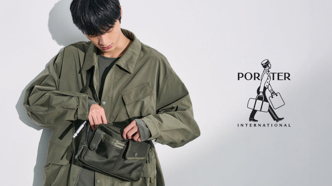 Model wearing an olive green jacket and using a green Porter International crossbody bag with multiple compartments, minimalist design.